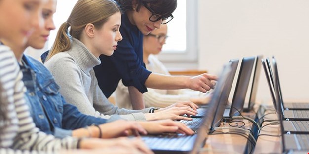 Studenter som arbetar tillsammans vid datorer. Foto.