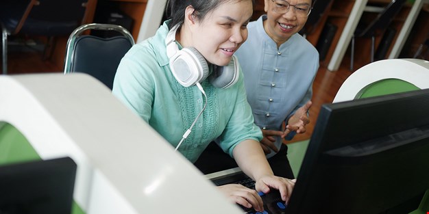 En synskadad person som arbetar vid en dator. Foto