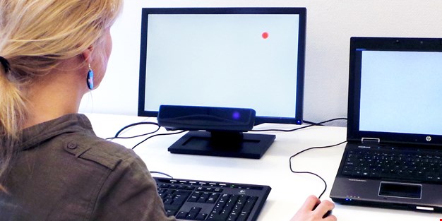 Kvinna använder eyetracking på en datorskärm. Fotografi